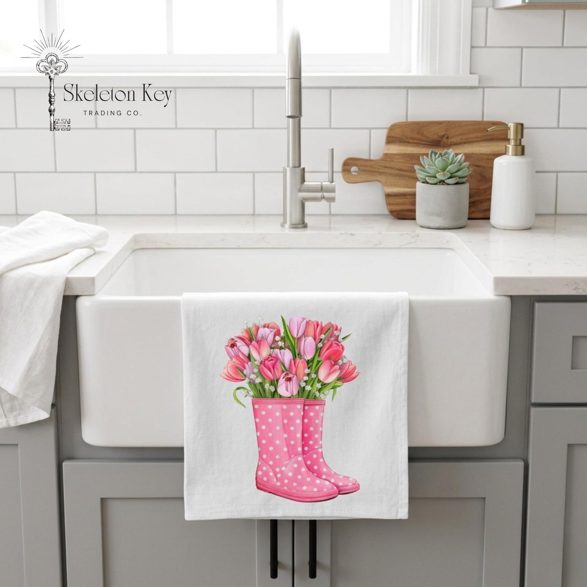 Kitchen sink area with a towel featuring pink rain boots and tulips hanging on a white cabinet.