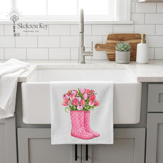 Kitchen sink area with a towel featuring pink rain boots and tulips hanging on a white cabinet.