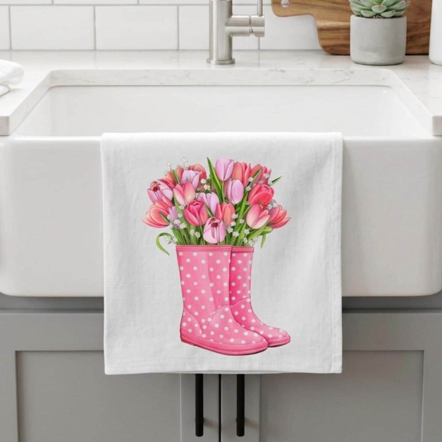 Kitchen towel with pink rain boots and tulips hanging over a sink