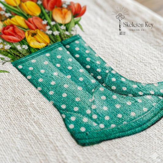 Green polka dot boot with a bouquet of tulips on a textured surface, featuring the Skeleton Key Trading Co. logo.