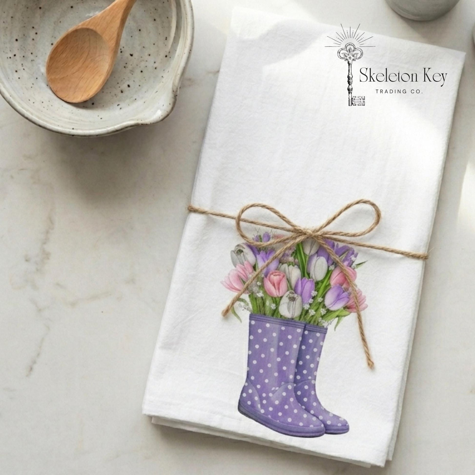 Napkin with floral design of purple boots and flowers, tied with twine, on a marble surface.
