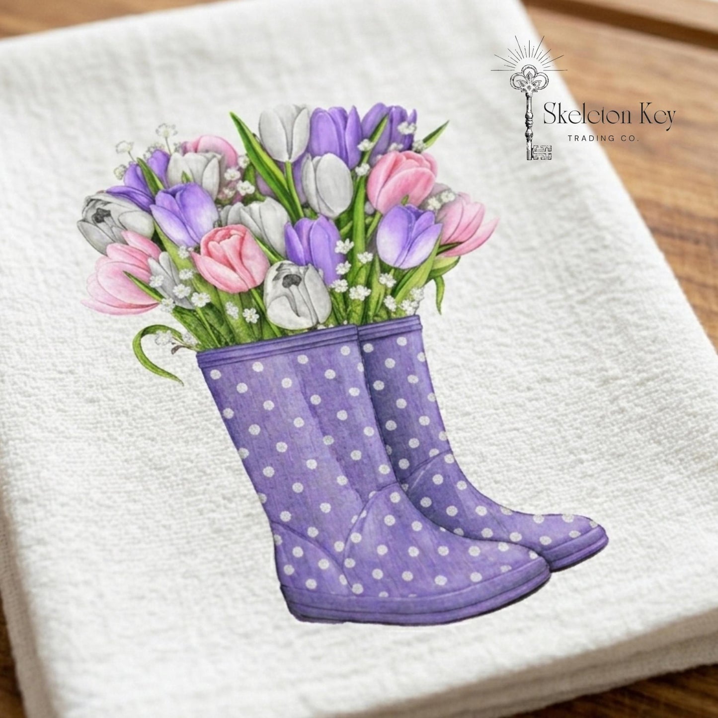 Purple polka dot boots with tulips on a white towel, brand 'Skeleton Key Trading Co' visible