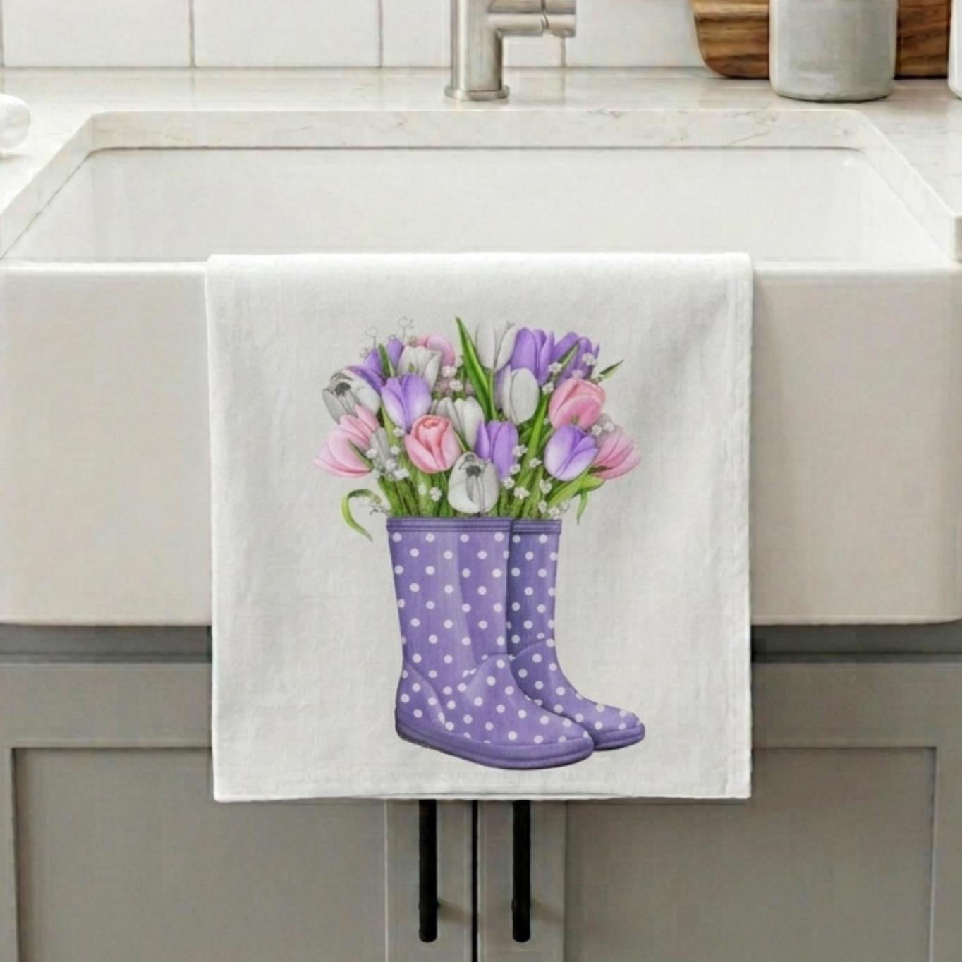 Towel with purple wellington boots and flowers hanging on a kitchen towel rack.