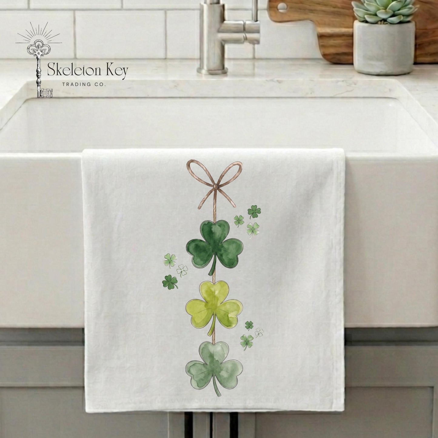 White towel with green shamrock design hanging on a kitchen sink.