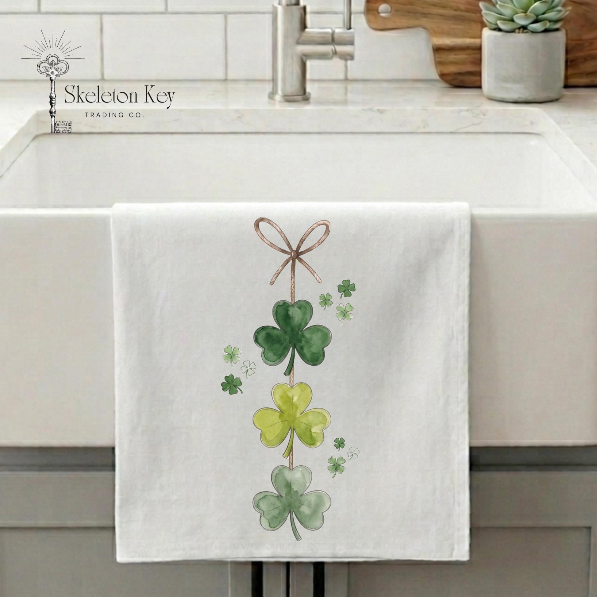 White towel with green shamrock design hanging on a kitchen sink.