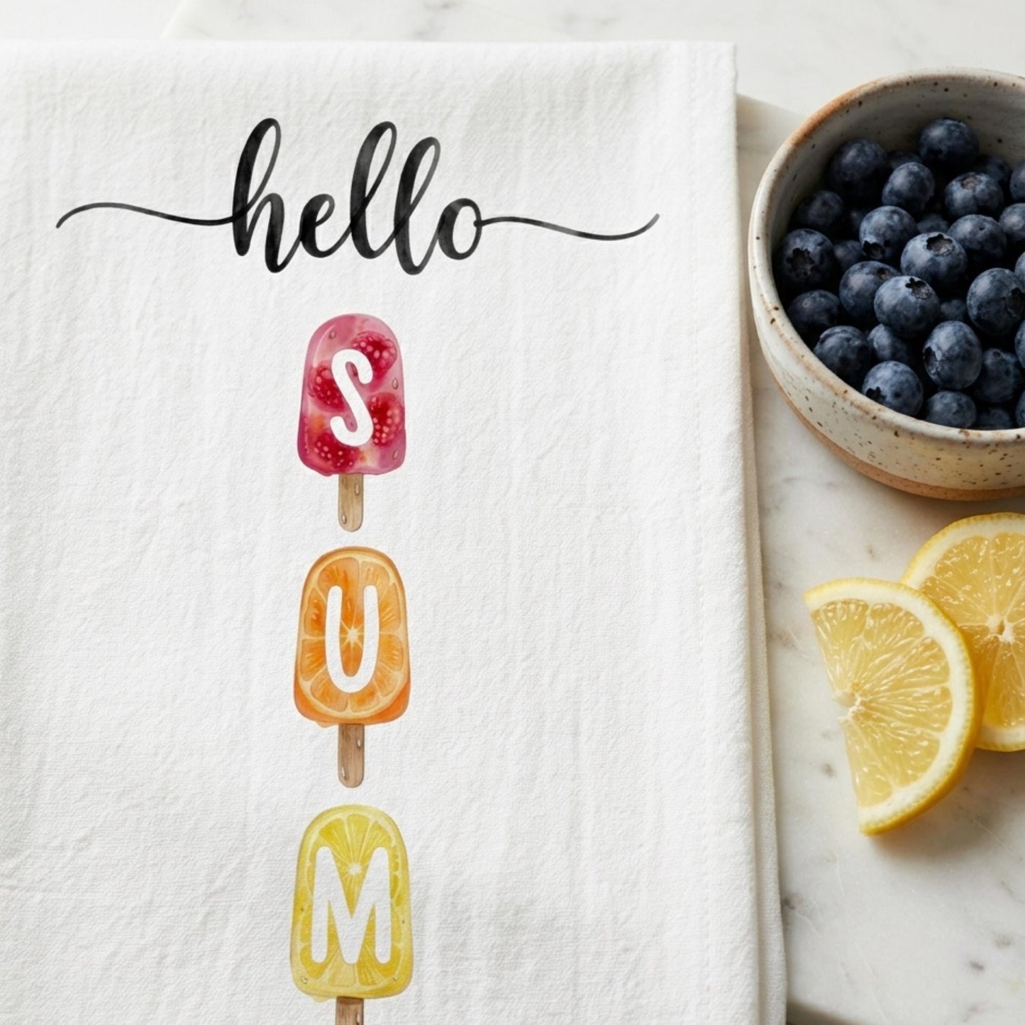Text 'hello SUMMER' on a towel with popsicles, bowl of blueberries, and lemon slices on a marble surface.