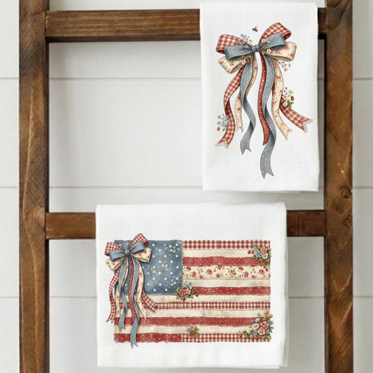 Set of two patriotic kitchen towels featuring vintage Americana flag and farmhouse bow designs displayed on wooden ladder