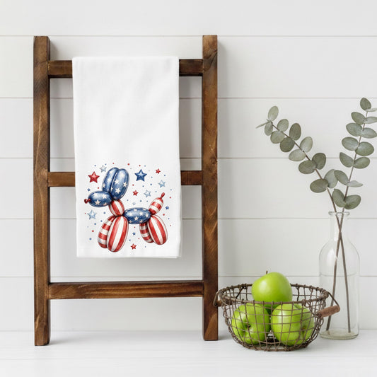 White towel with patriotic balloon dog design on a wooden ladder against a white wall.