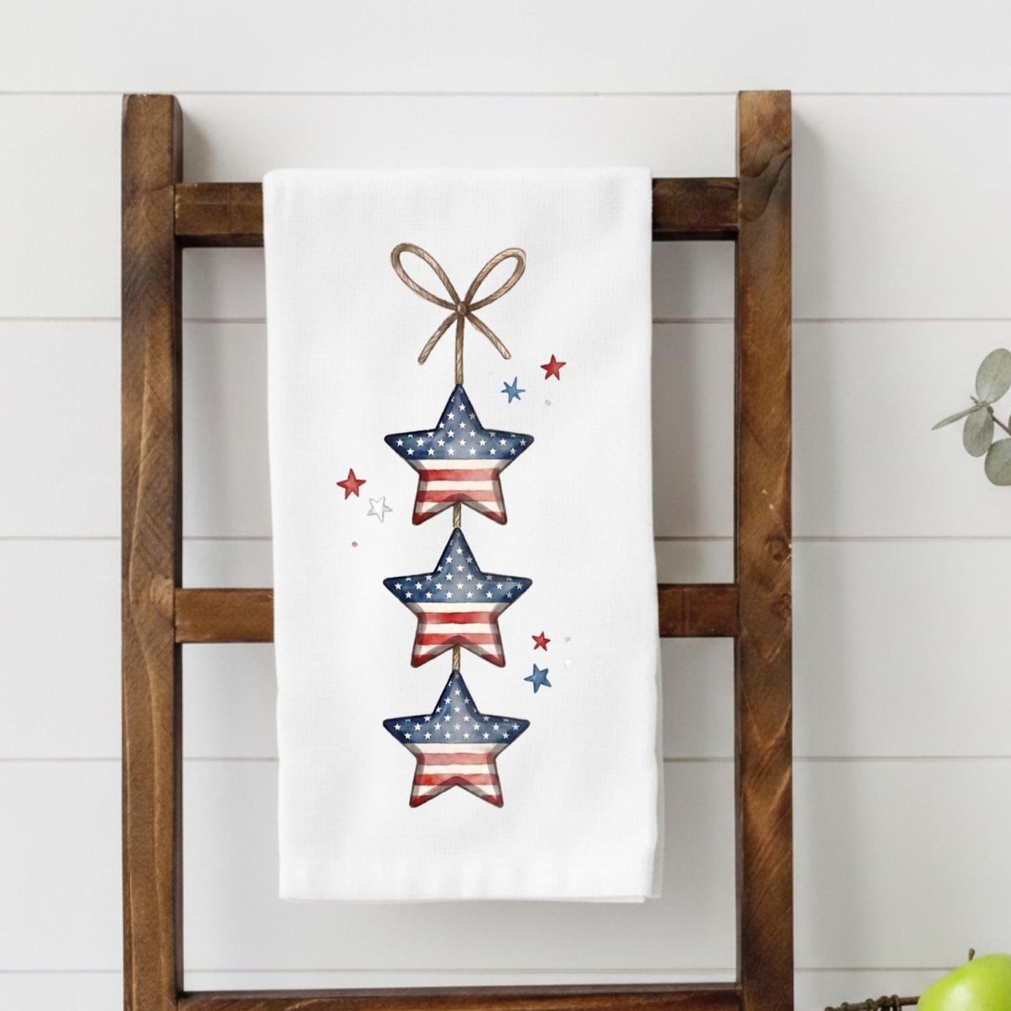 Decorative towel with star design hanging on a wooden ladder against a white wall.