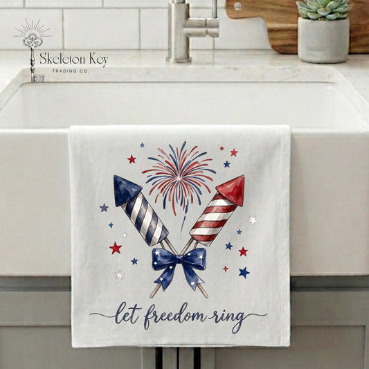 Decorative towel with firework design and 'let freedom ring' text on a kitchen sink.