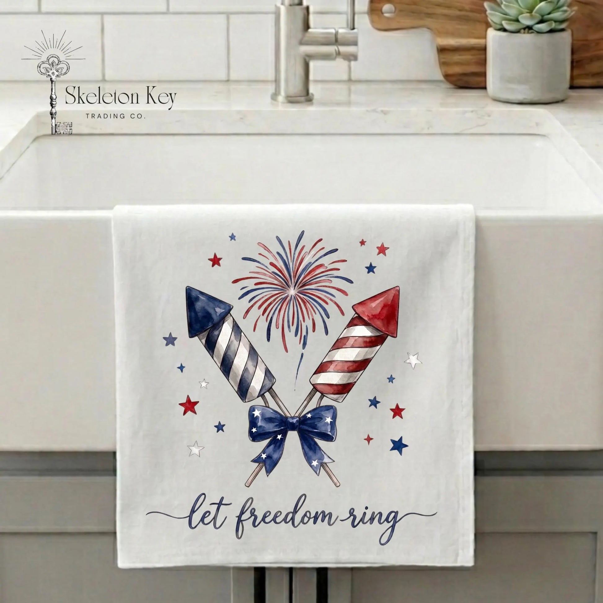 Patriotic tea towel hanging on farmhouse sink featuring fireworks rockets and Let Freedom Ring artwork