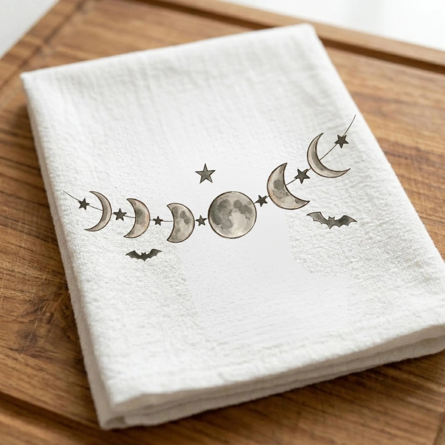 Moon phases tea towel featuring watercolor lunar phase artwork with stars and bats on white kitchen towel