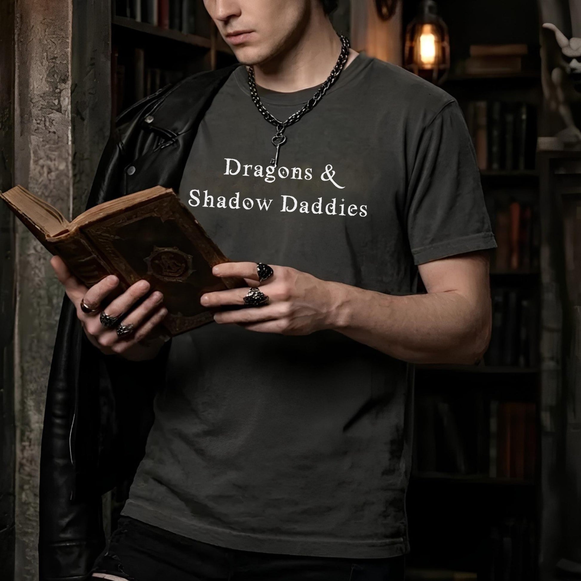 Man wearing Dragons & Shadow Daddies shirt while reading a fantasy novel in a dark academia library setting