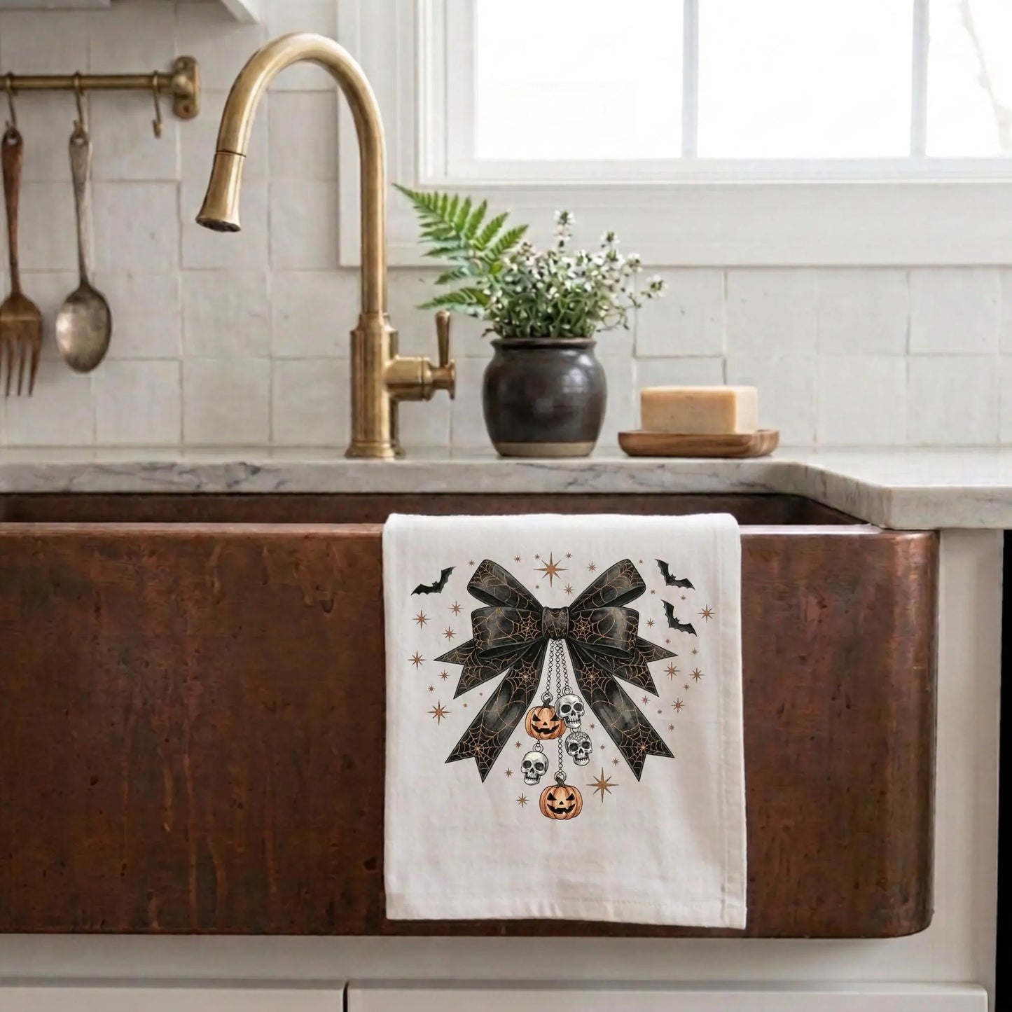 Kitchen sink with a decorative towel featuring a bow and Halloween-themed design.
