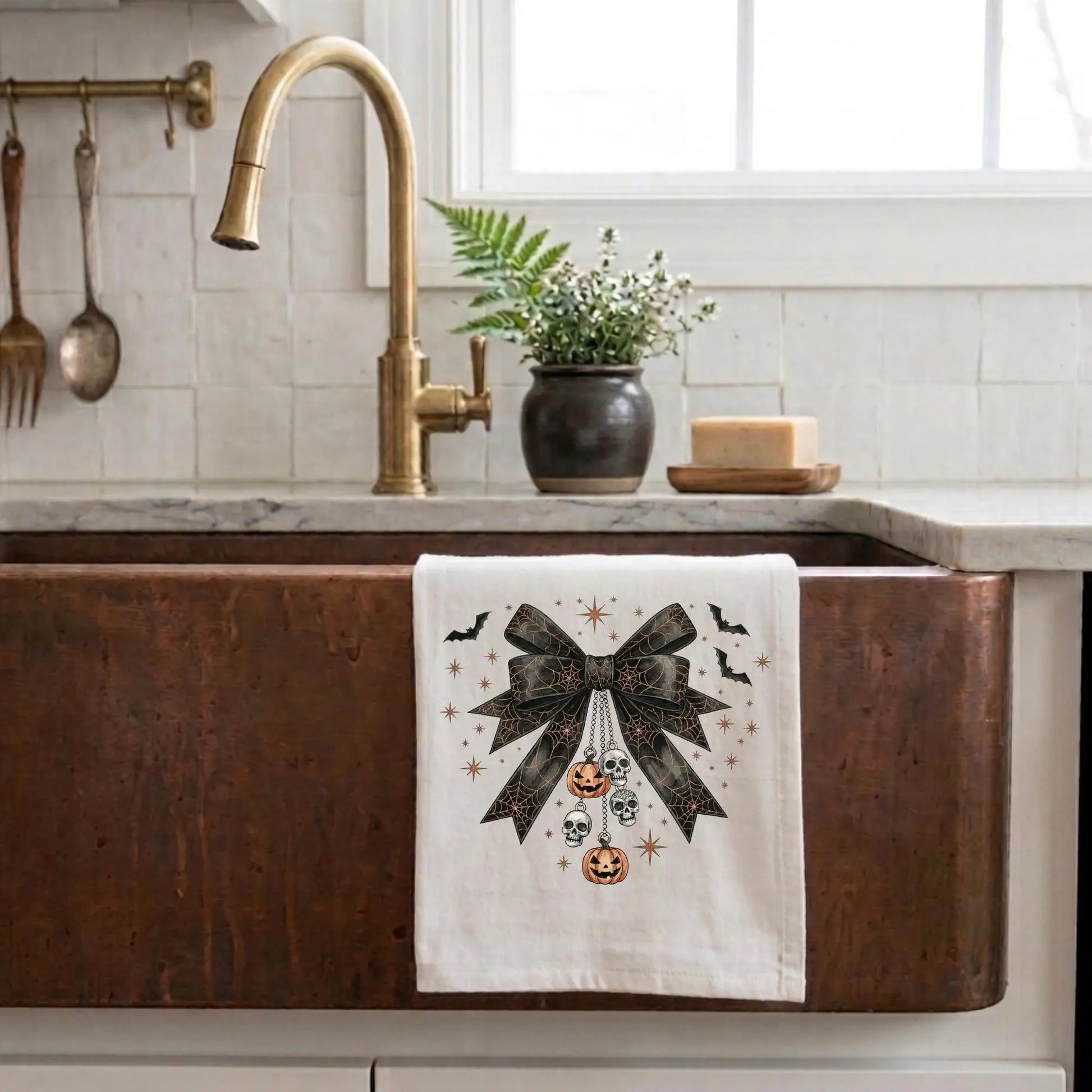 Kitchen sink with a decorative towel featuring a bow and Halloween-themed design.