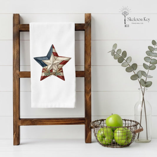 Americana barn star tea towel with weathered wood textures, patriotic colors, and primitive country decor details
